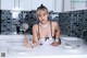 A woman sitting at a kitchen counter holding a ladle.