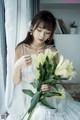 A woman in a white dress holding a bunch of white flowers.