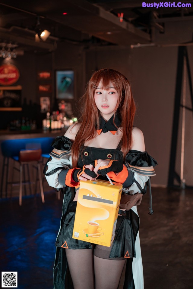 A woman in a black and orange outfit holding a box of coffee.