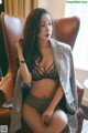 A woman sitting in a chair wearing a suit and lingerie.