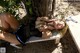 A woman laying on a bench under a tree.