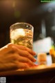 A person holding a glass of beer with ice in it.