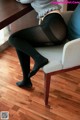 A woman sitting on a chair wearing black tights.