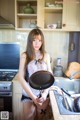 A woman in lingerie holding a frying pan in a kitchen.