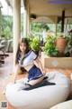 A woman in a school uniform sitting on a bean bag chair.