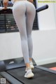 A woman in white leggings is running on a treadmill.