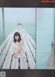 A woman sitting on a wooden pier by the water.