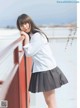 A woman in a school uniform leaning against a railing.