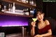 A woman sitting at a bar holding a drink.