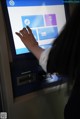 A person using an atm machine with a touch screen.